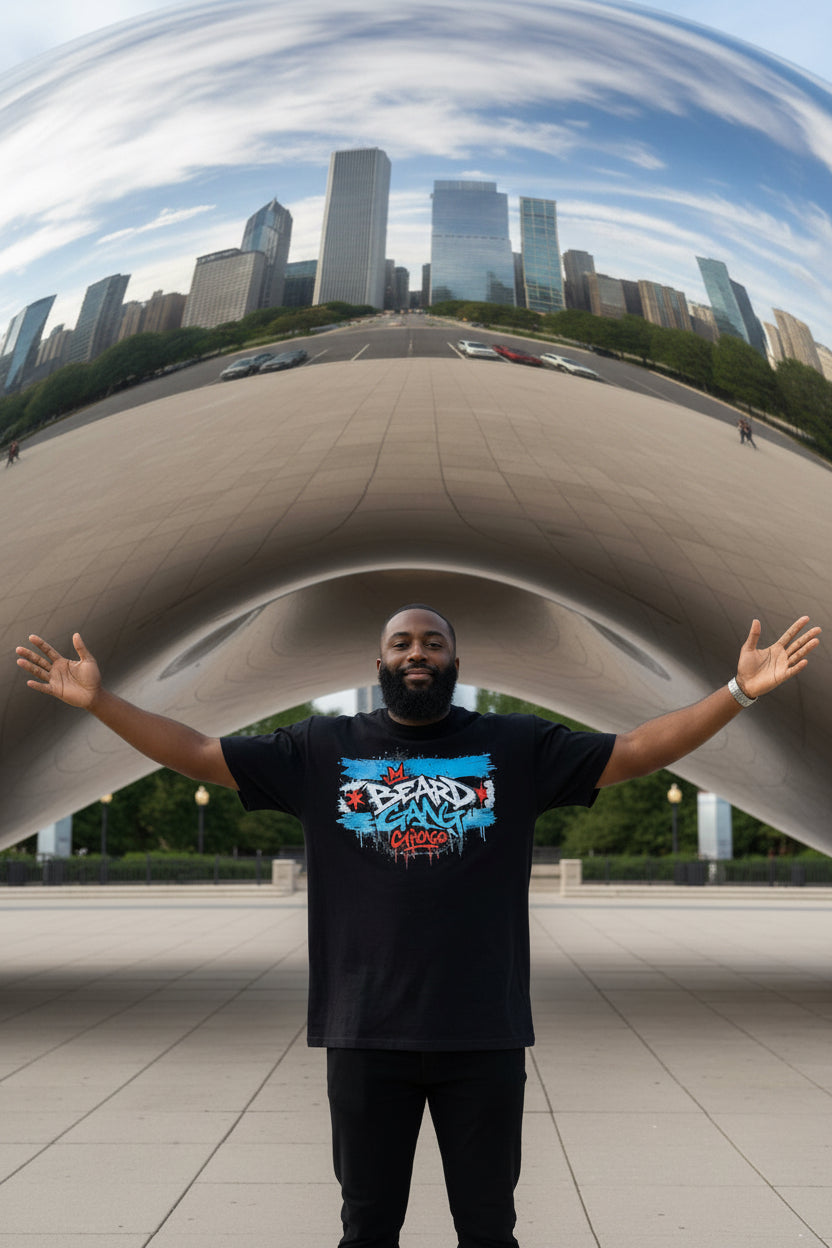 A bearded African American stands with open arms in front of The Bean in Chicago wearing a black T-shirt featuring a colorful 'Beard Gang Chicago' graffiti-style graphic on the front.